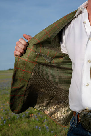 Person wearing a green tweed jacket with a white shirt in an outdoor setting