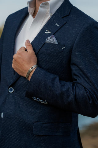Man wearing a navy suit with a white shirt and patterned pocket square.