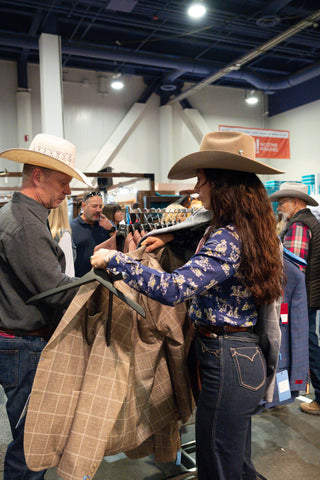 Cowboy sport coat shopping experience at a western trade show, with customers browsing tailored jackets and western wear in person.